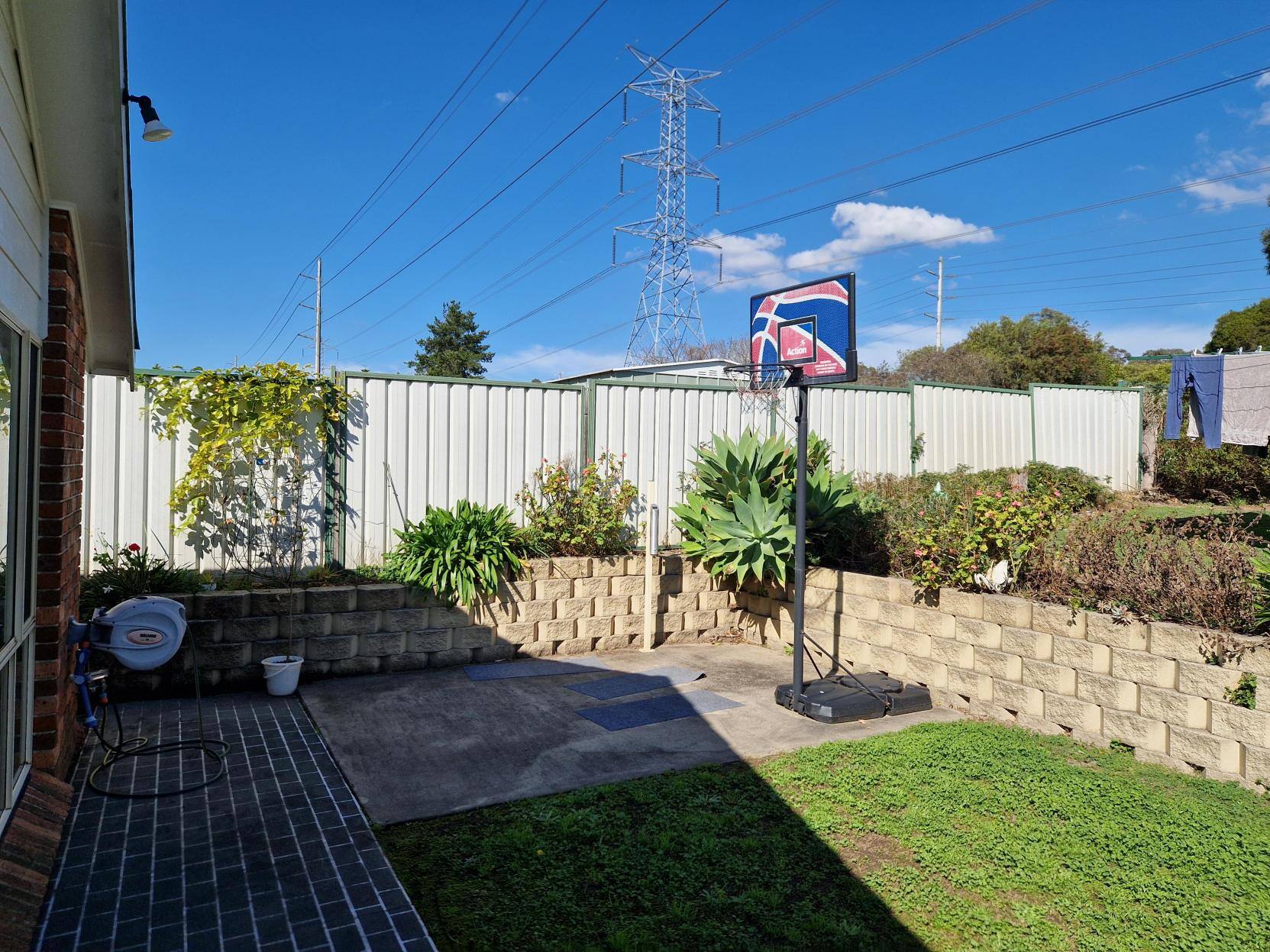 Garden with lawn and patio, featuring a basketball net.