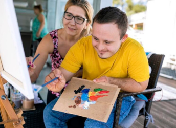 A man and a woman painting on a canvas.