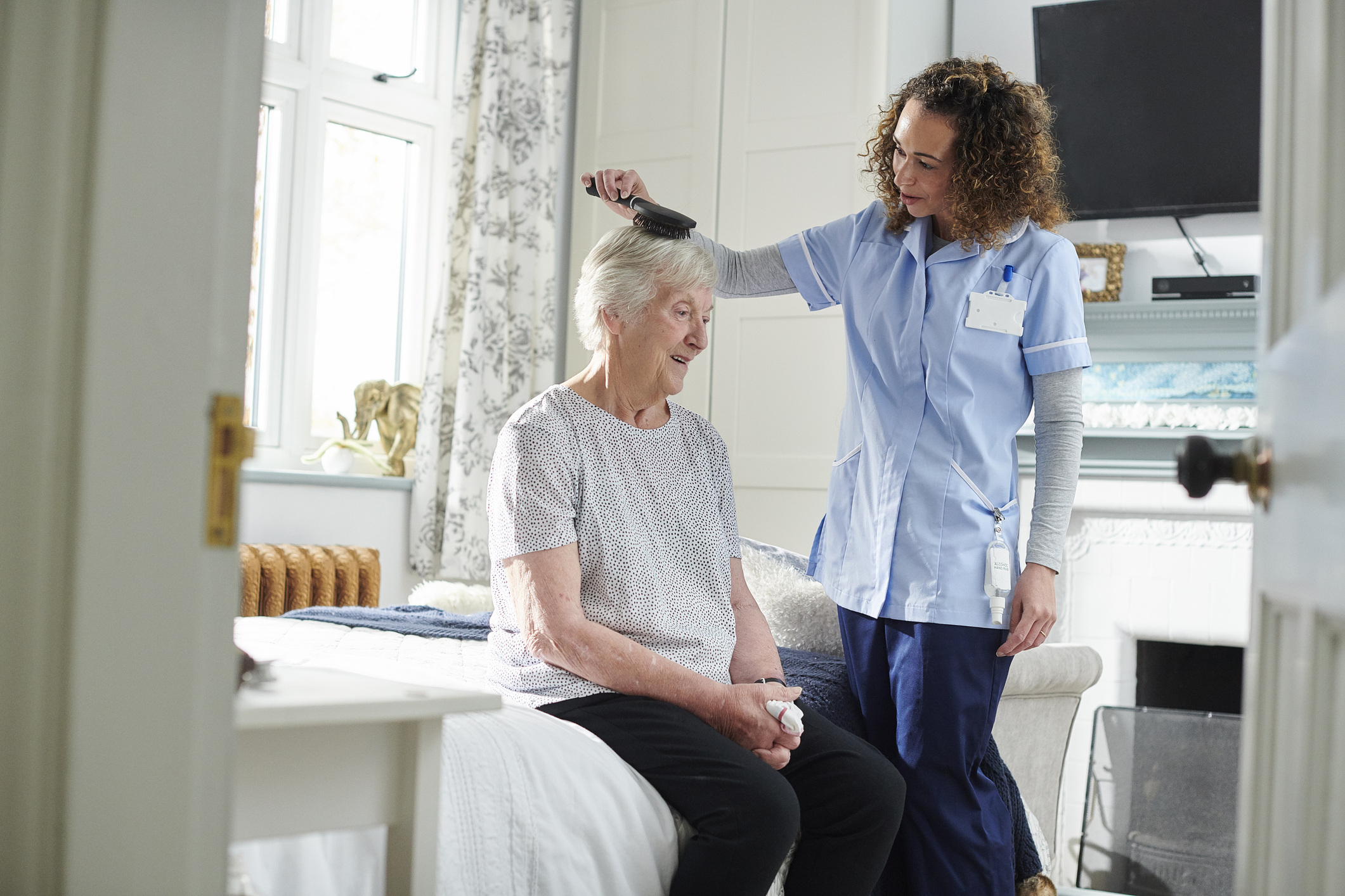 home carer helping senior woman get ready in her bedroom